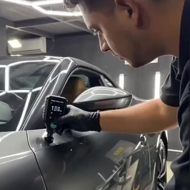 Juan Sáez midiendo el espesor de laca de un vehículo en el taller Fullshine de Concepción